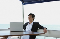 Young man on yacht, using laptop - Yukmin