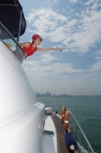 Young woman on yacht, pointing into distance - Yukmin