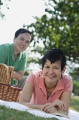 Mature couple having a picnic in the park, smiling at camera - Alex Mares-Manton