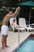Young man cleaning swimming pool - Alex Mares-Manton