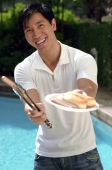 Young man offering hot dog and smiling at camera - Cedric Lim