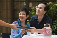 Mature couple being handed menu in restaurant - Cedric Lim