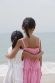 Young sisters hugging and looking out at sea - Yukmin