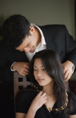 Man putting necklace around woman's neck - Yukmin