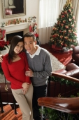 Young couple on the stairs at Christmas time smiling at camera - Alex Mares-Manton
