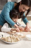 Mother and daughter making dumplings in the kitchen - Alex Mares-Manton