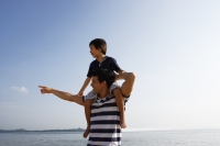 Father piggybacking son at the beach - Yukmin