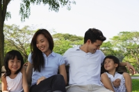 Young family sitting on park bench - Yukmin