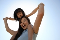 Mother piggybacking daughter smiling at the camera - Yukmin