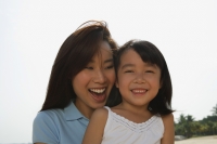 Mother and daughter smiling at the beach - Yukmin