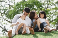 Young family sitting on ground at the park - Yukmin