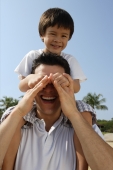 Father carrying son on his shoulders st the beach - Yukmin