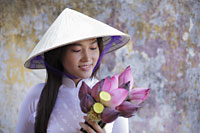 Young woman wearing traditional Vietnamese outfit holding lotus flowers - Alex Mares-Manton
