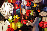 Young woman standing in front of colorful, hanging lanterns - Alex Mares-Manton