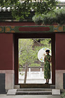 Young woman wearing Chinese traditional dress standing in doorway holding an umbrella - Alex Mares-Manton