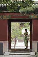 Young woman wearing Chinese traditional dress standing in a doorway holding an umbrella - Alex Mares-Manton