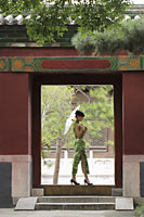 Young woman walking through a Chinese doorway holding an umbrella - Alex Mares-Manton