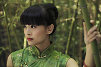 Young woman wearing a traditional Chinese dress and standing in front of bamboo trees - Alex Mares-Manton