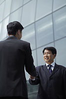Businessmen shaking hands in front of a building - Alex Mares-Manton