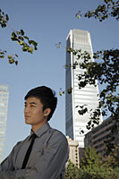 Profile of young man standing in front of skyscraper, China - Alex Mares-Manton