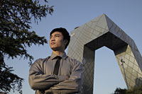 Young man standing in front of CCTV Building, Beijing, China - Alex Mares-Manton
