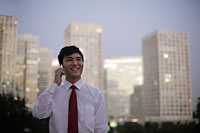 Young man talking on phone in front of buildings in the evening, China - Alex Mares-Manton