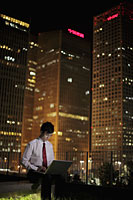 Young man working on his lap top with buildings as backdrop - Alex Mares-Manton