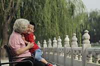 Grandmother hugging and kissing grandson in a park - Alex Mares-Manton
