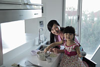 Mother teaching daughter how to cook - Alex Mares-Manton