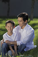 Father and son sitting on grass together - Alex Mares-Manton