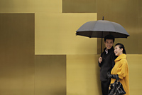 Young couple walking on street holding an umbrella - Alex Mares-Manton
