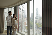 Young couple looking out large windows at view - Alex Mares-Manton