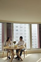 Young couple sitting at table in their condo - Alex Mares-Manton