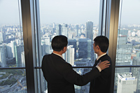 Two men talking in front of window with a view of the city of Beijing - Alex Mares-Manton