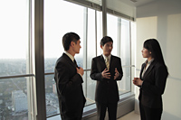Three businesspeople talking in front of a window - Alex Mares-Manton