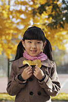 Young girl smiling and holding Autumn leaves outdoors - Alex Mares-Manton