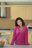 Young woman wearing pink smiling in her kitchen - Alex Mares-Manton