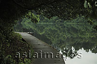 Wooden path along the edge of a lake with trees reflected in the water - Alex Mares-Manton