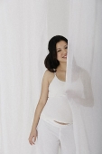 Pregnant woman standing behind curtain - Asia Images Group