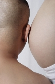 Man leaning ear against pregnant stomach - Asia Images Group