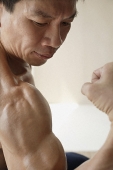 Profile of man flexing muscles - Asia Images Group