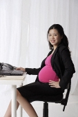Profile of pregnant businesswoman at desk - Asia Images Group