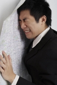 frustrated man leaning against map - Asia Images Group