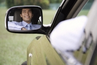 Reflection of smiling man in car rear view mirror - Asia Images Group