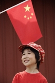 Portrait of little girl standing under Chinese flag - Asia Images Group