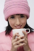 Young woman in pink hat and vest with coffee cup - Asia Images Group