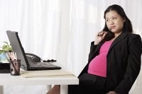 Profile of pregnant businesswoman at desk - Asia Images Group