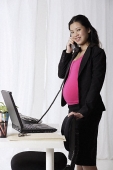 Profile of pregnant businesswoman on phone - Asia Images Group