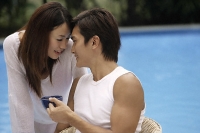 Young couple touching foreheads poolside - Asia Images Group