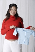 Pregnant woman holding baby clothes - Asia Images Group